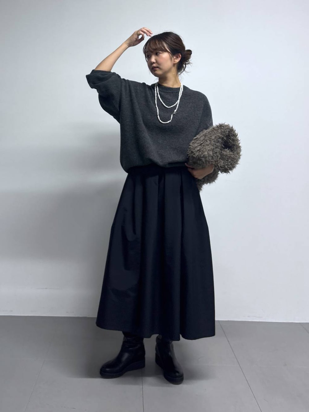 グレー系のニット/セーター、ブラウン系のハンドバッグ、ブラック系のブーツを着用したレディースの秋コーディネートの4枚目の写真