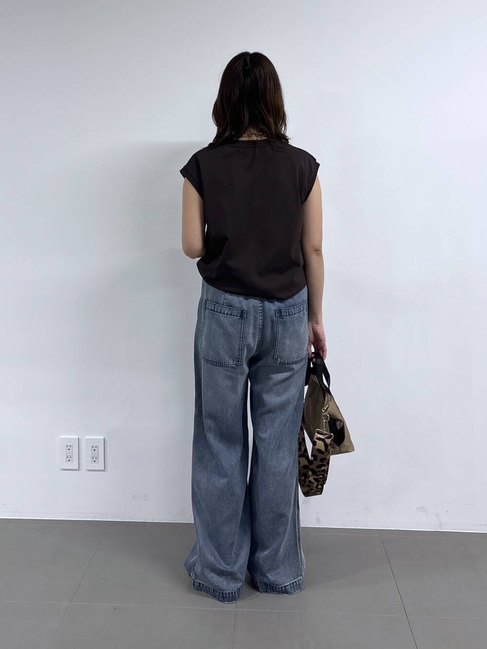 イエロー系のトートバッグ、ブラウン系のTシャツ/カットソー、ブルー系のデニムパンツを着用したレディースの春コーディネートの4枚目の写真