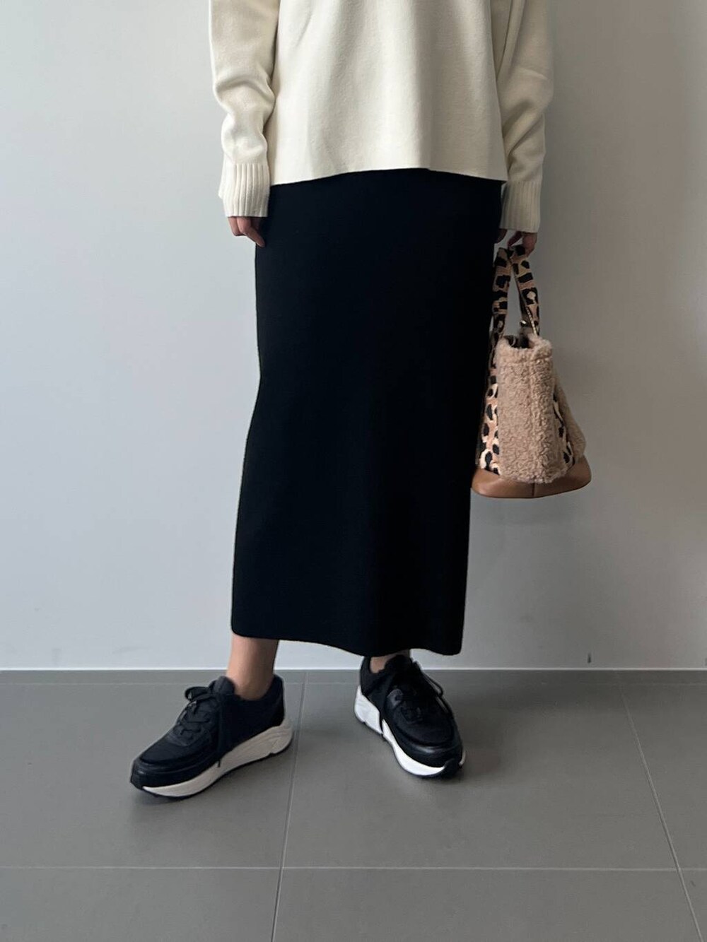 ブラウン系のトートバッグ、ブラック系のスカート、ブラック系のスニーカーを着用したレディースの冬コーディネートの4枚目の写真