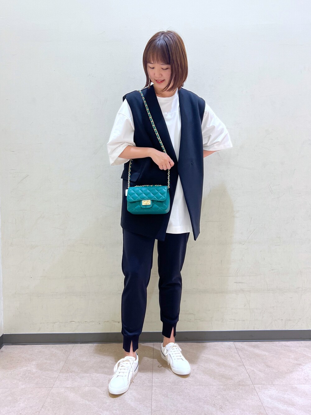 ホワイト系のTシャツ/カットソー、ブラック系のベスト、ベージュ系のバッグを着用したレディースの夏コーディネートの2枚目の写真