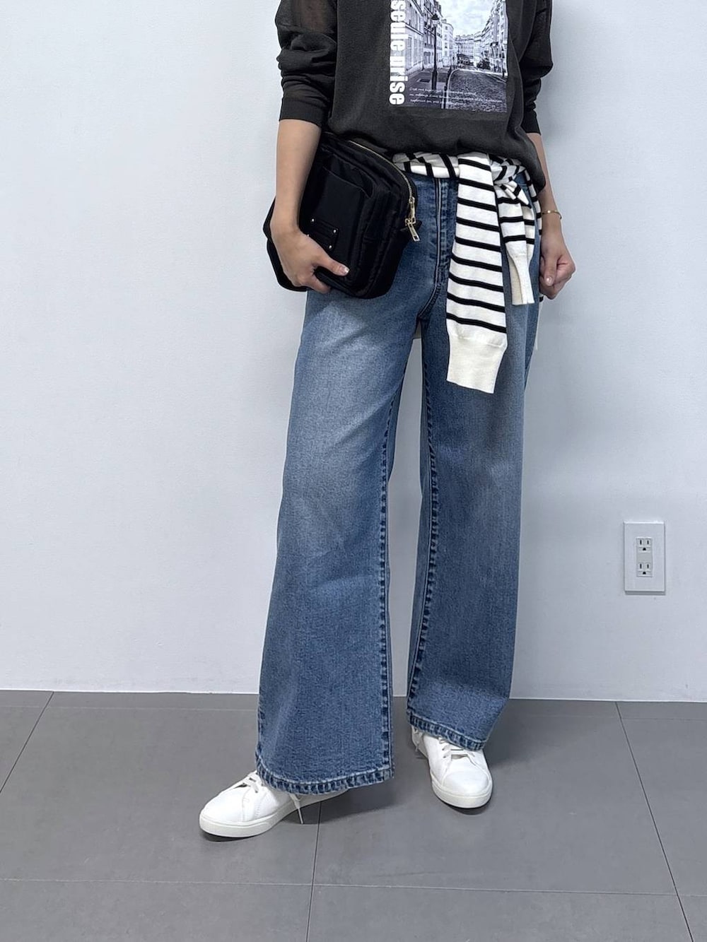 グレー系のニット/セーター、ブラック系のショルダーバッグ、ブルー系のデニムパンツを着用したレディースの秋コーディネートの4枚目の写真