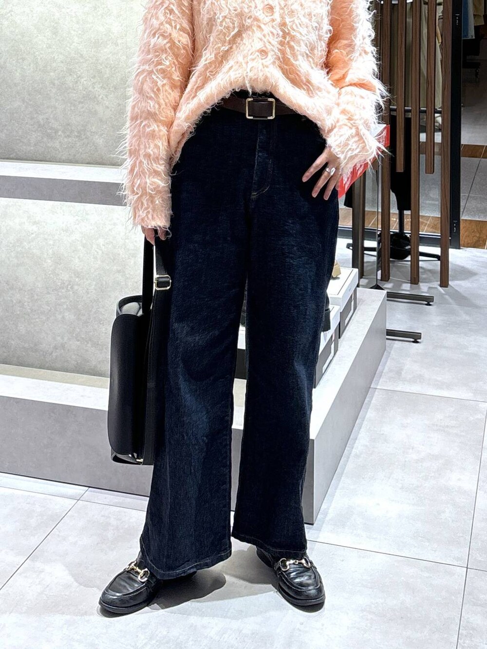 ブルー系のデニムパンツ、ピンク系のカーディガン/ボレロ、ブラック系のショルダーバッグを着用したレディースの冬コーディネートの4枚目の写真