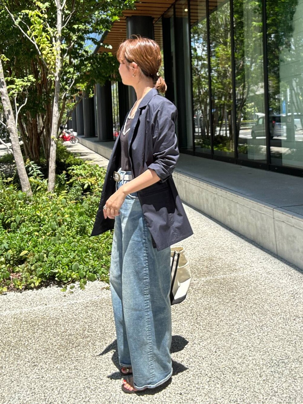 ホワイト系のショルダーバッグ、ブルー系のデニムパンツ、ブルー系のテーラードジャケットを着用したレディースの夏コーディネートの3枚目の写真