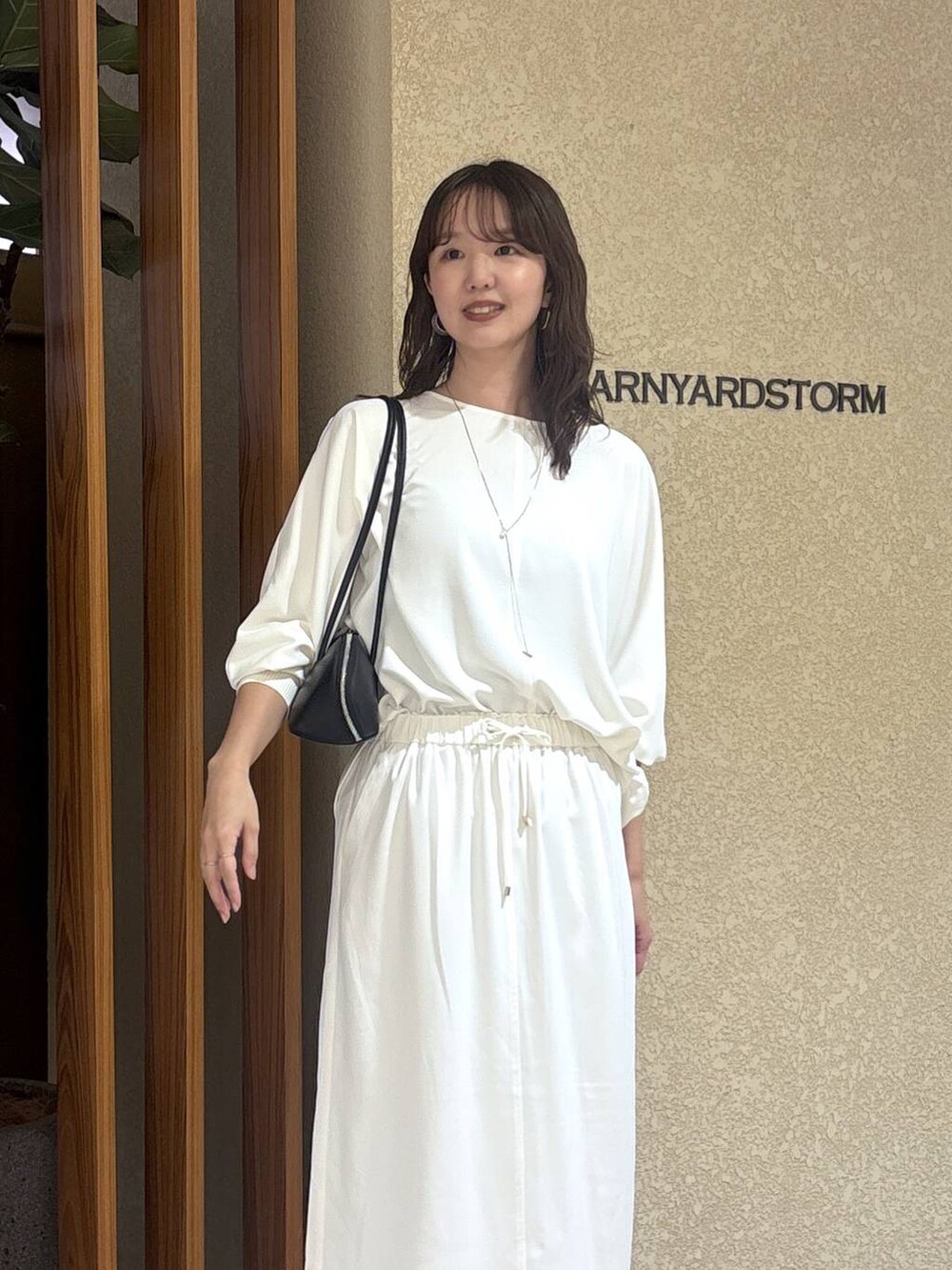 ホワイト系のスカート、ホワイト系のTシャツ/カットソー、ブラック系のハンドバッグを着用したレディースの冬コーディネートの3枚目の写真