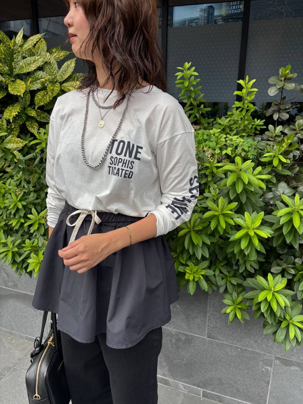 ブラック系のデニムパンツ、ブラック系のベスト、ホワイト系のTシャツ/カットソーを着用したレディースの夏コーディネートの5枚目の写真