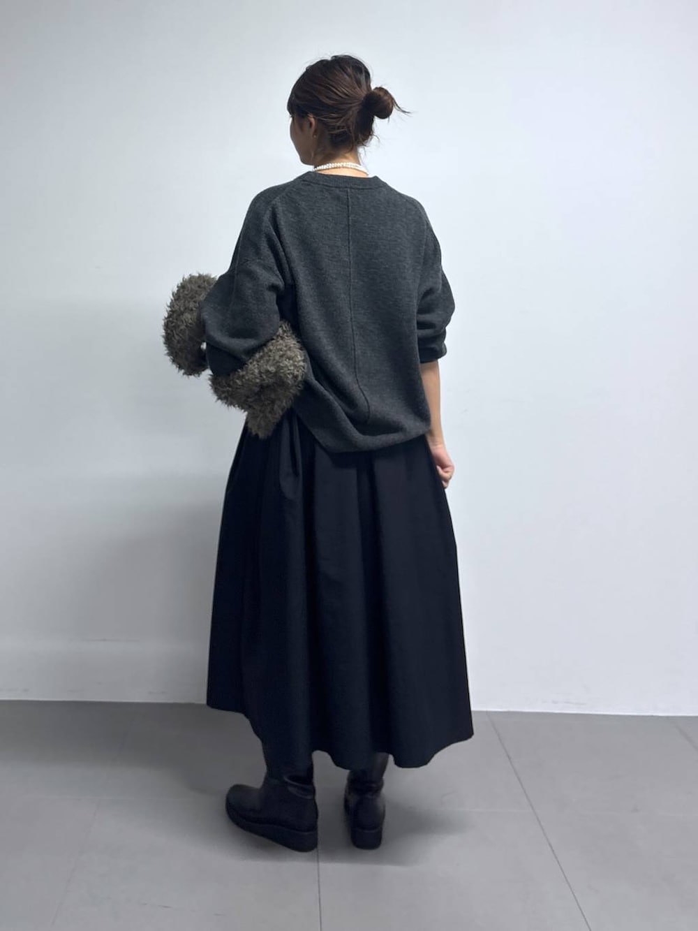 グレー系のニット/セーター、ブラウン系のハンドバッグ、ブラック系のブーツを着用したレディースの秋コーディネートの3枚目の写真