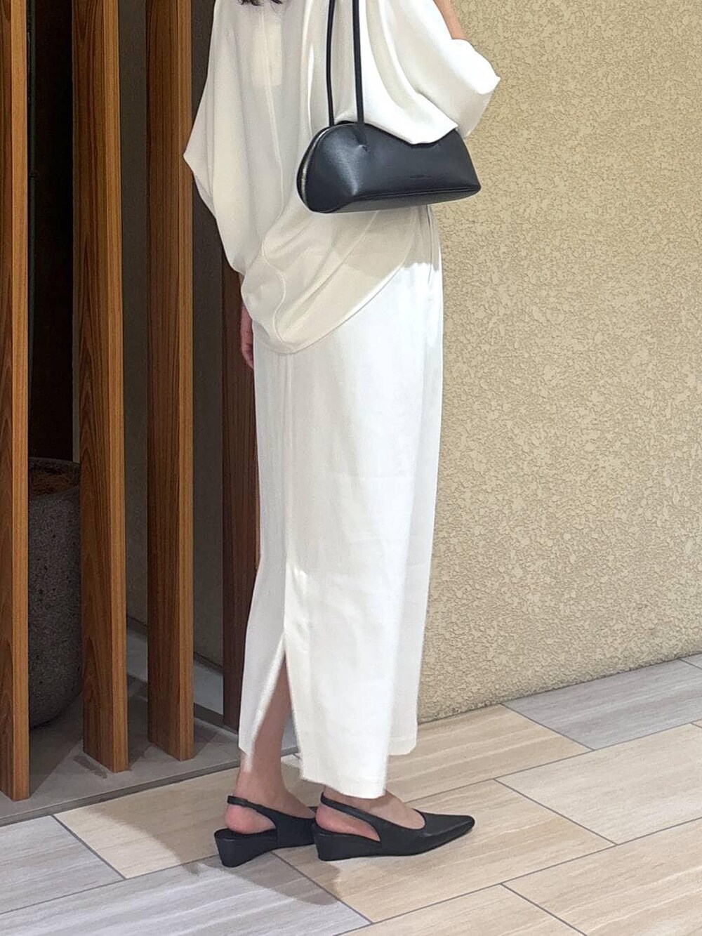 ホワイト系のスカート、ホワイト系のTシャツ/カットソー、ブラック系のハンドバッグを着用したレディースの冬コーディネートの6枚目の写真