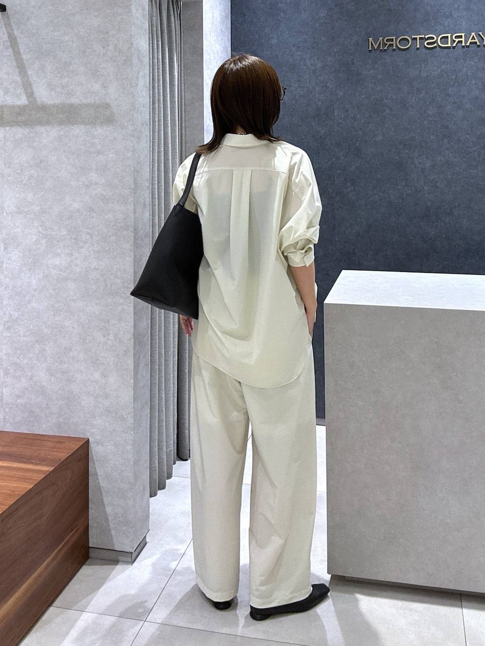 ブラック系のパンプス、ブラック系のトートバッグ、ホワイト系のシャツ/ブラウスを着用したレディースの夏コーディネートの5枚目の写真