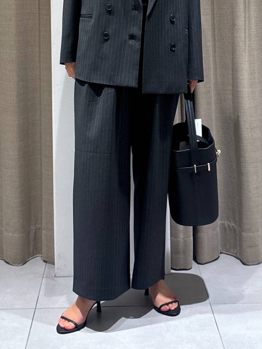 グレー系のスラックス、グレー系のテーラードジャケット、ブラック系のハンドバッグを着用したレディースの秋コーディネートの5枚目の写真