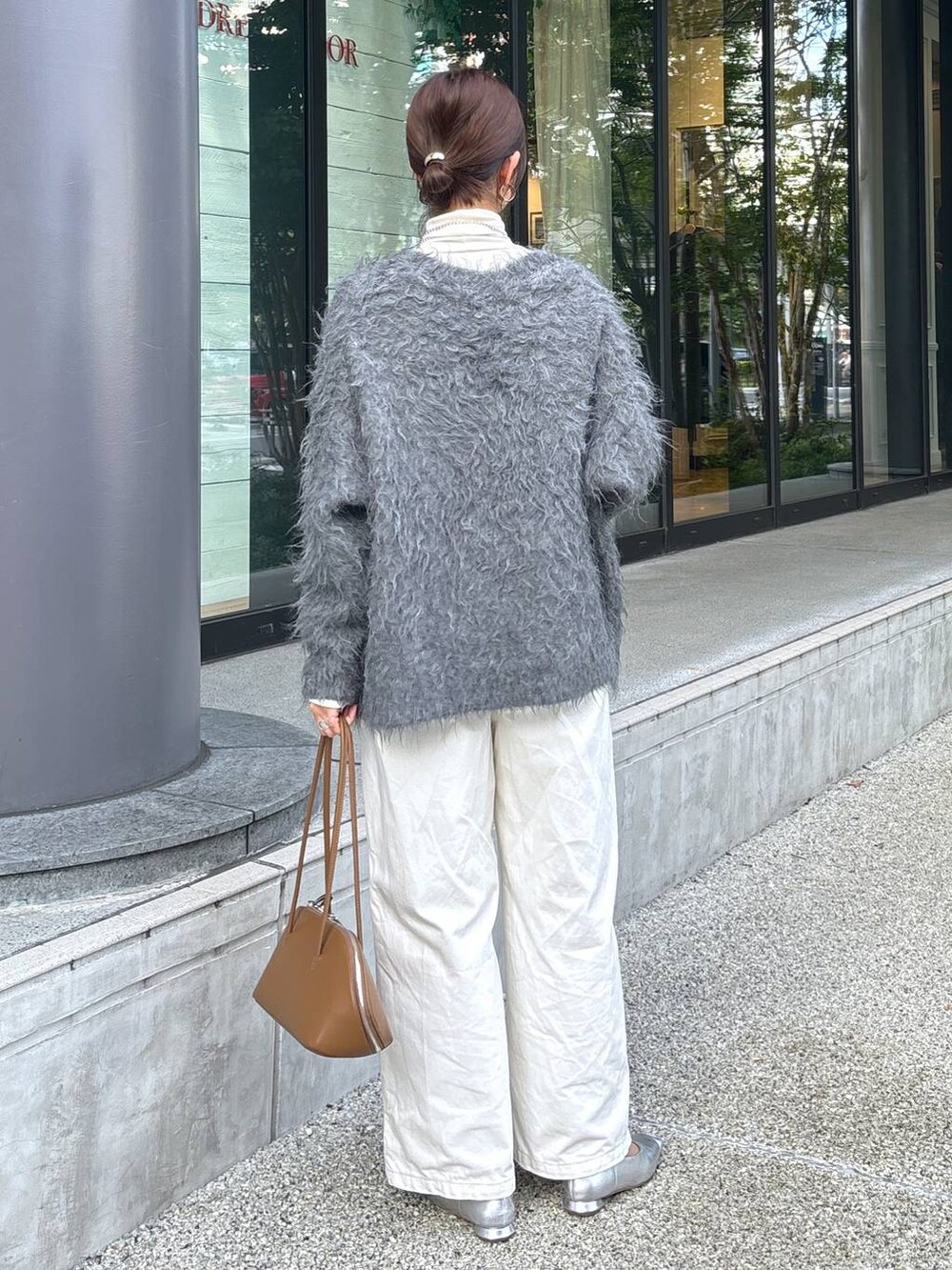 イエロー系のトートバッグ、シルバー系のパンプス、ホワイト系のデニムパンツを着用したレディースの秋コーディネートの5枚目の写真