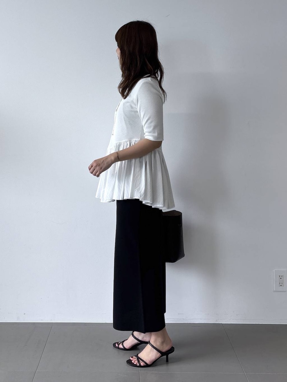 ブラック系のスカート、ホワイト系のTシャツ/カットソーを着用したレディースの夏コーディネートの3枚目の写真
