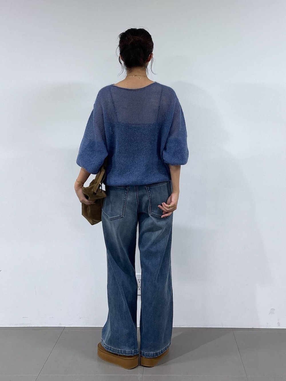 ブルー系のデニムパンツ、イエロー系のブーツ、イエロー系のトートバッグを着用したレディースの秋コーディネートの5枚目の写真