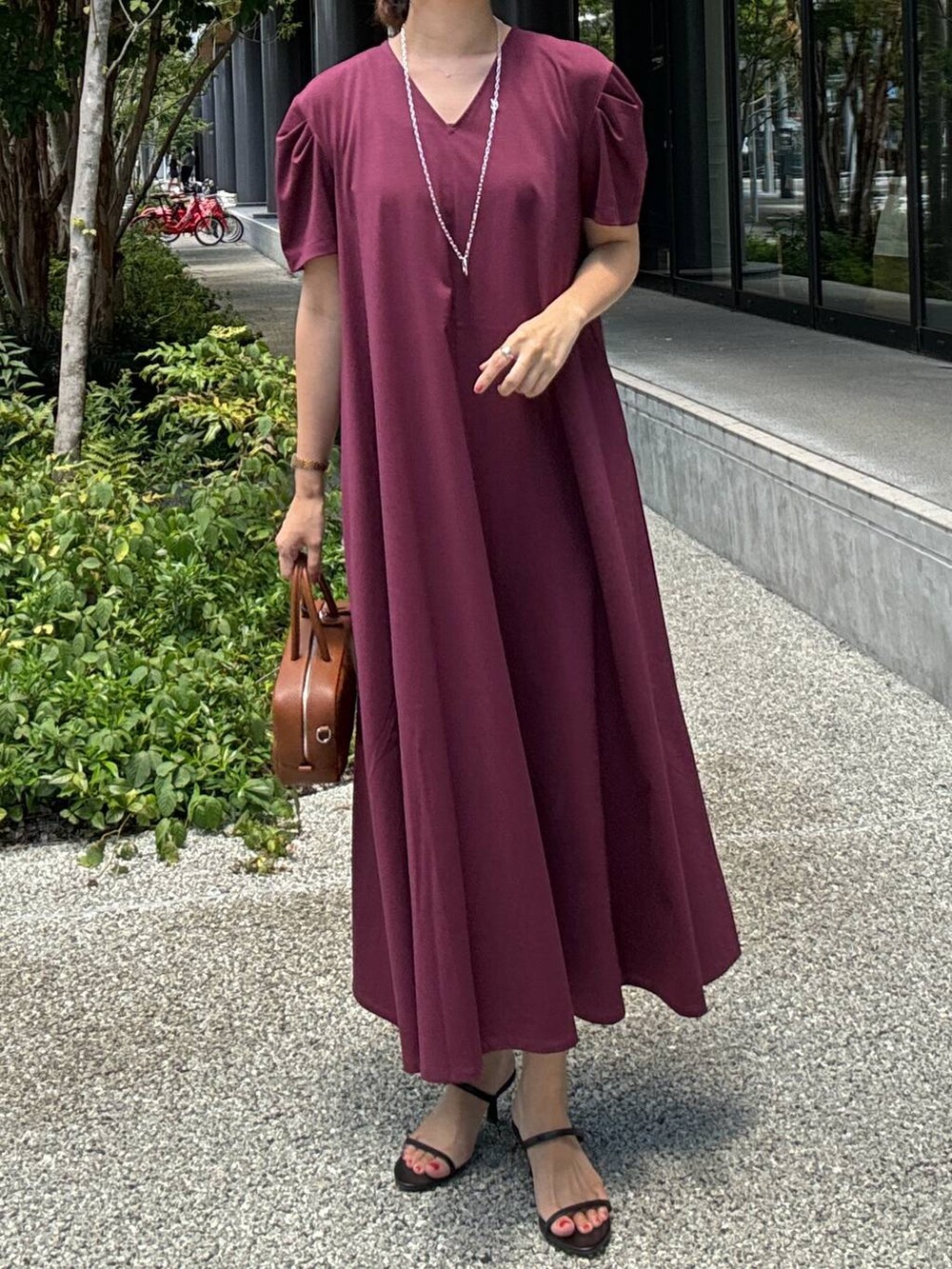 ブラック系のスリッポン、ブラウン系のハンドバッグ、レッド系のワンピースを着用したレディースの夏コーディネートの2枚目の写真