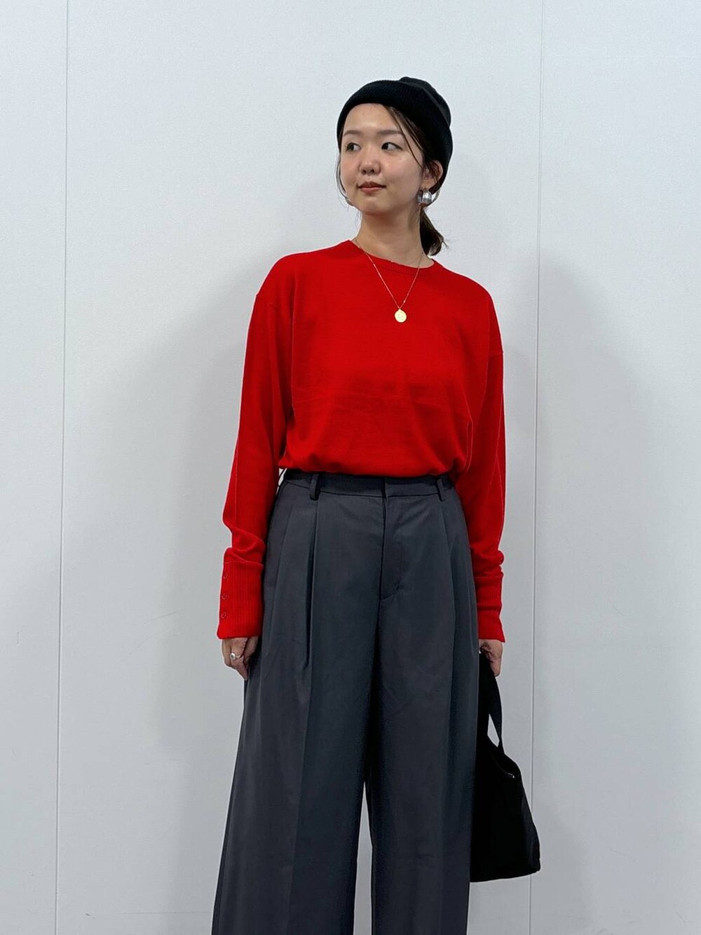 グレー系のスラックス、ブラック系のトートバッグ、レッド系のニット/セーターを着用したレディースの秋コーディネートの2枚目の写真