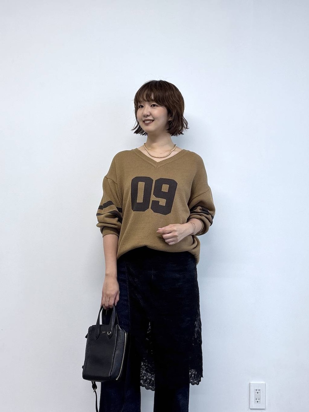 ブラック系のローファー、ブルー系のデニムパンツ、ベージュ系のニット/セーターを着用したレディースの秋コーディネートの2枚目の写真