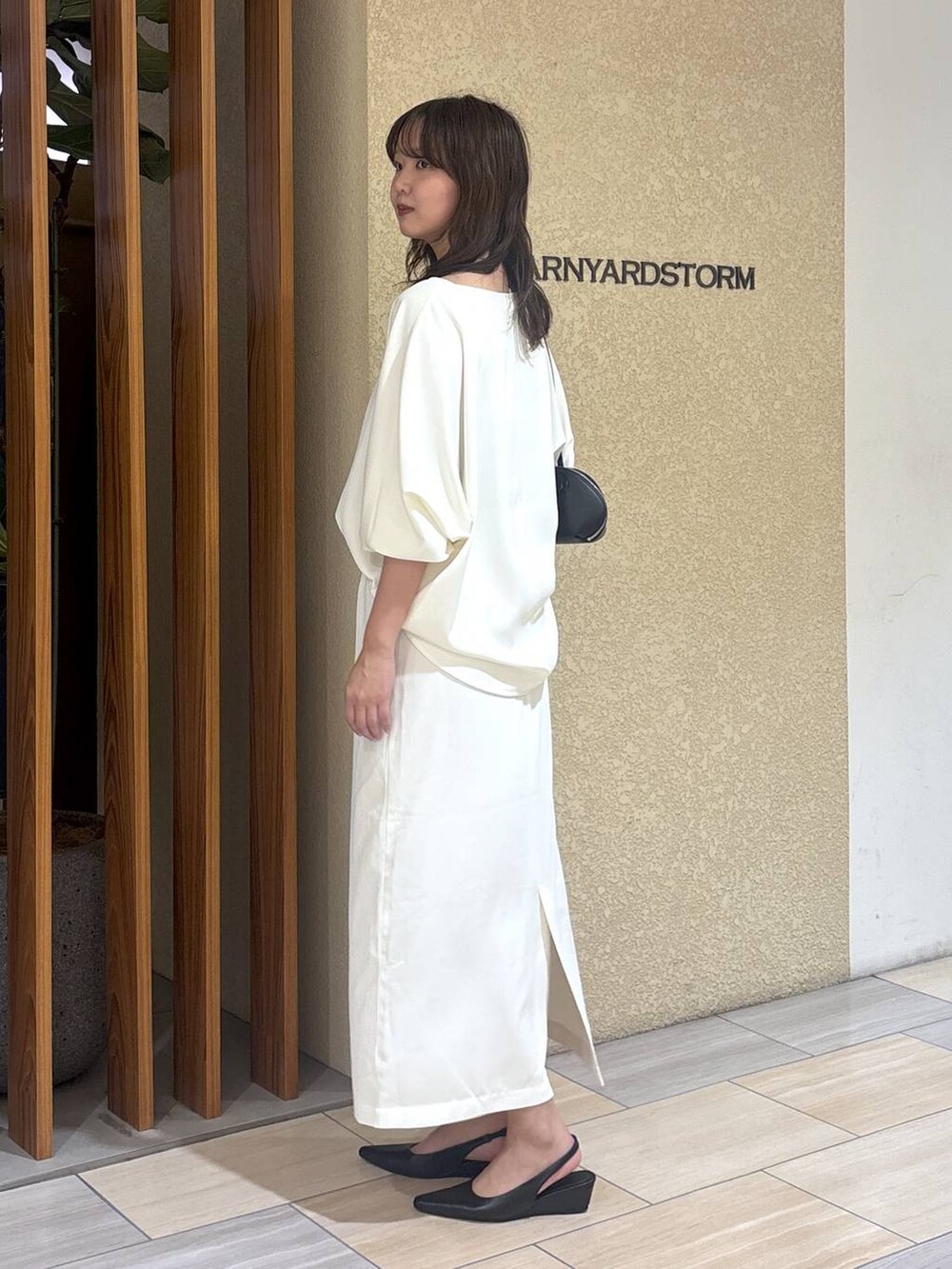 ホワイト系のスカート、ホワイト系のTシャツ/カットソー、ブラック系のハンドバッグを着用したレディースの冬コーディネートの2枚目の写真