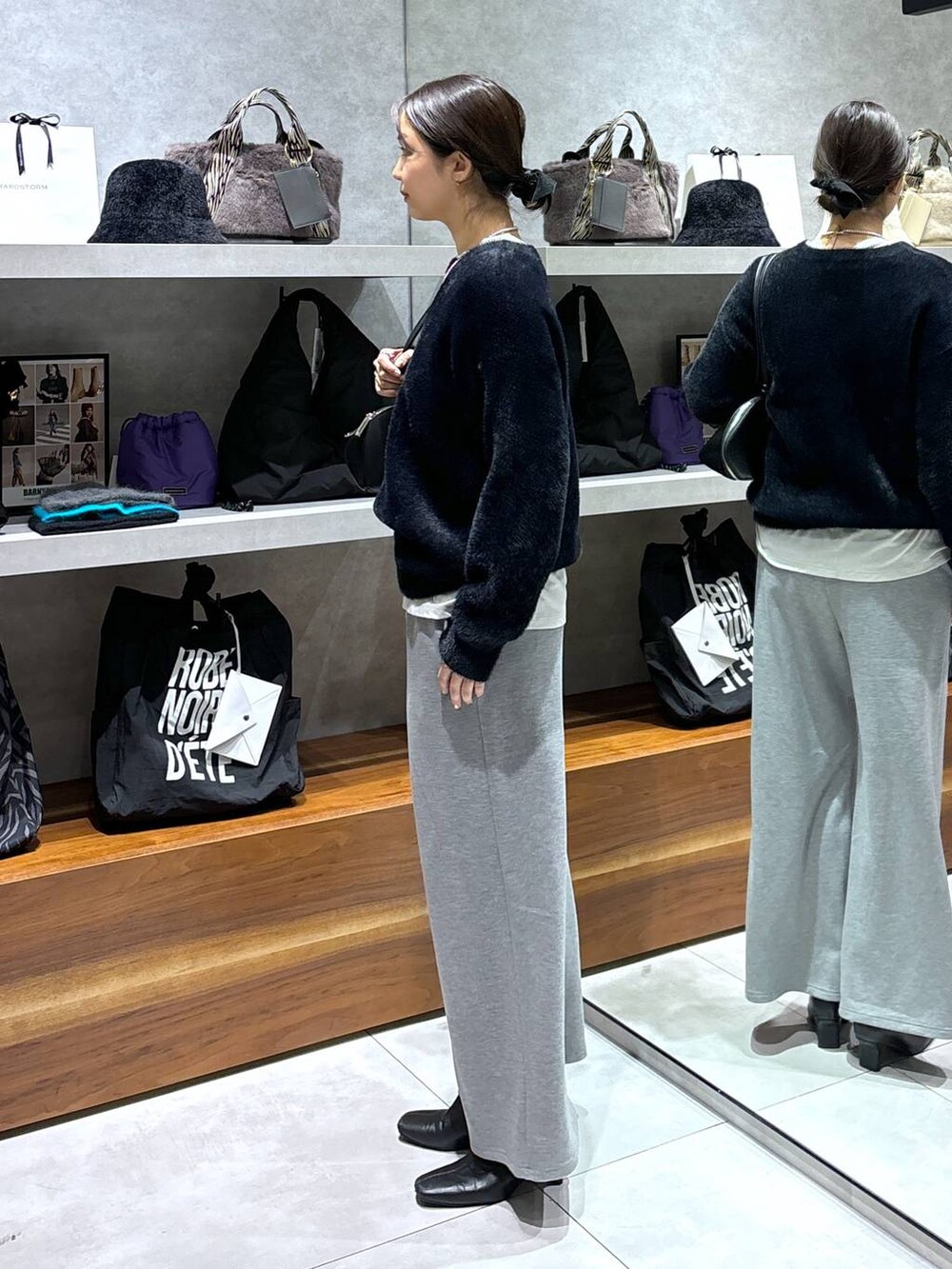 ブラック系のトートバッグ、ホワイト系のTシャツ/カットソー、ブラック系のニット/セーターを着用したレディースの冬コーディネートの2枚目の写真