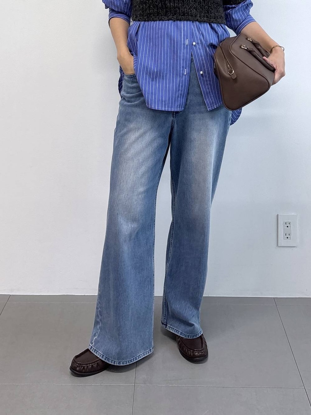 ブルー系のシャツ/ブラウス、ブラウン系のボストンバッグ、ブルー系のデニムパンツを着用したレディースの秋コーディネートの5枚目の写真