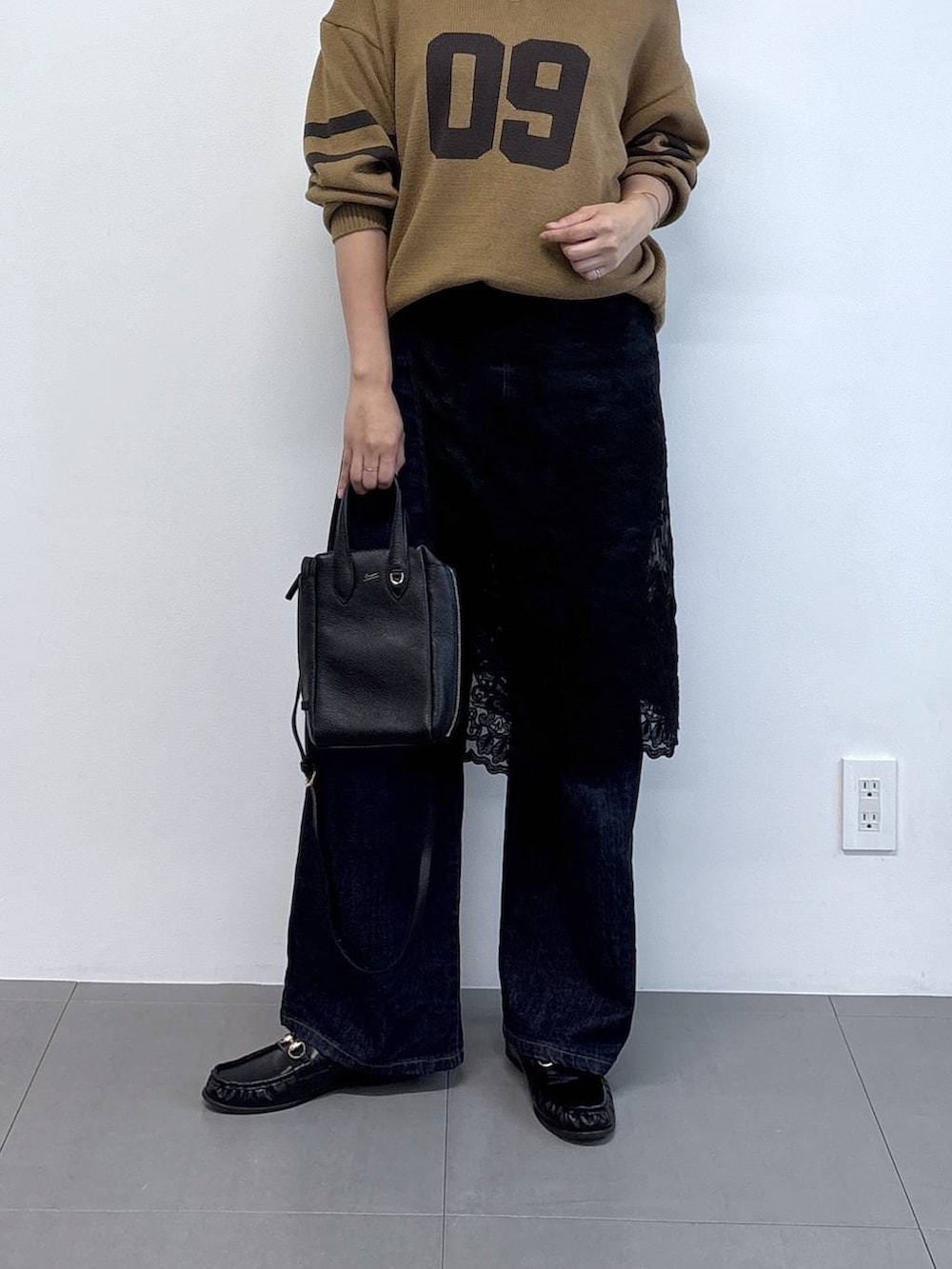 ブラック系のローファー、ブルー系のデニムパンツ、ベージュ系のニット/セーターを着用したレディースの秋コーディネートの6枚目の写真