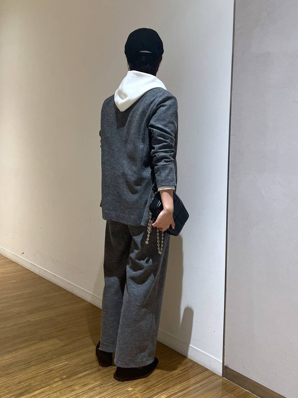 ブラック系のショルダーバッグ、ホワイト系のパーカー、グレー系のスラックスを着用したレディースの秋コーディネートの5枚目の写真