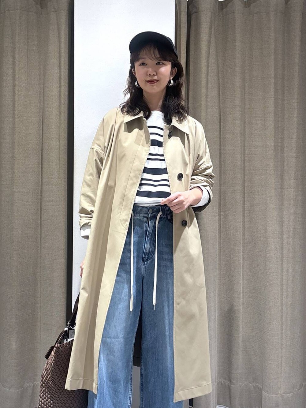 ホワイト系のTシャツ/カットソー、ブルー系のデニムパンツ、ベージュ系のステンカラーコートを着用したレディースの冬コーディネートの3枚目の写真