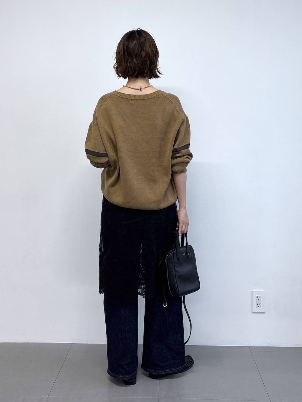 ブラック系のローファー、ブルー系のデニムパンツ、ベージュ系のニット/セーターを着用したレディースの秋コーディネートの4枚目の写真