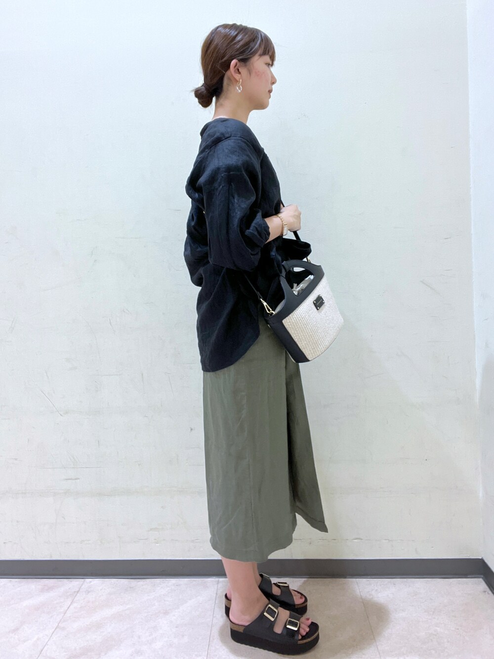 ブラック系のシャツ/ブラウス、ブラック系のバッグ、グリーン系のスカートを着用したレディースの夏コーディネートの3枚目の写真