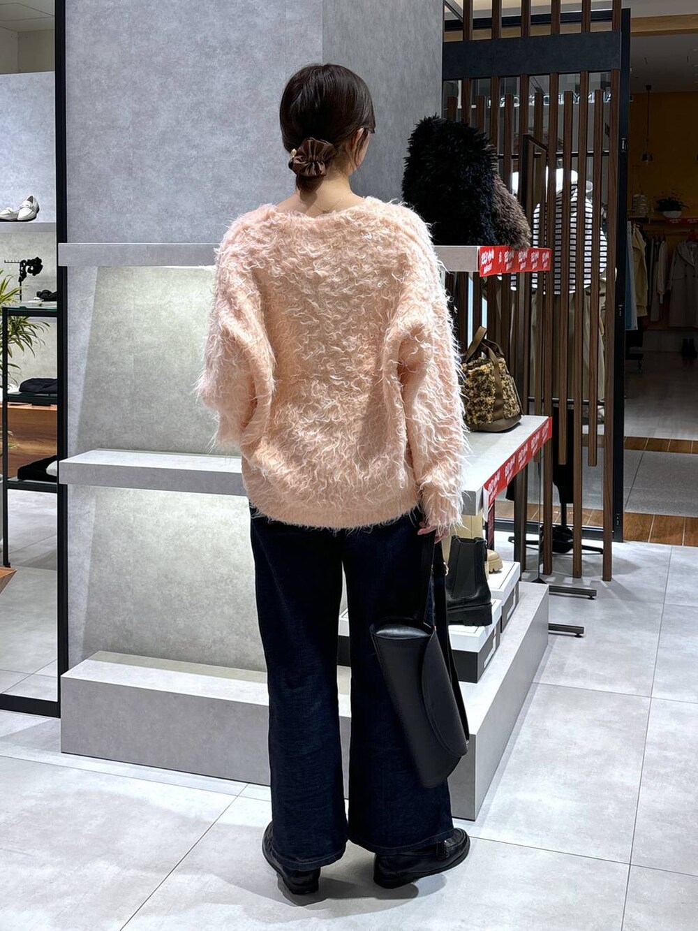 ブルー系のデニムパンツ、ピンク系のカーディガン/ボレロ、ブラック系のショルダーバッグを着用したレディースの冬コーディネートの5枚目の写真