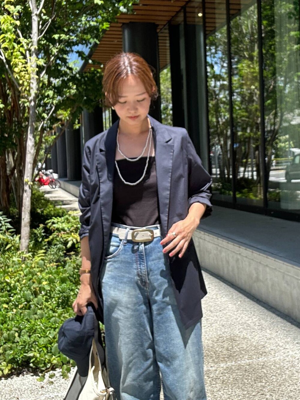 ホワイト系のショルダーバッグ、ブルー系のデニムパンツ、ブルー系のテーラードジャケットを着用したレディースの夏コーディネートの2枚目の写真