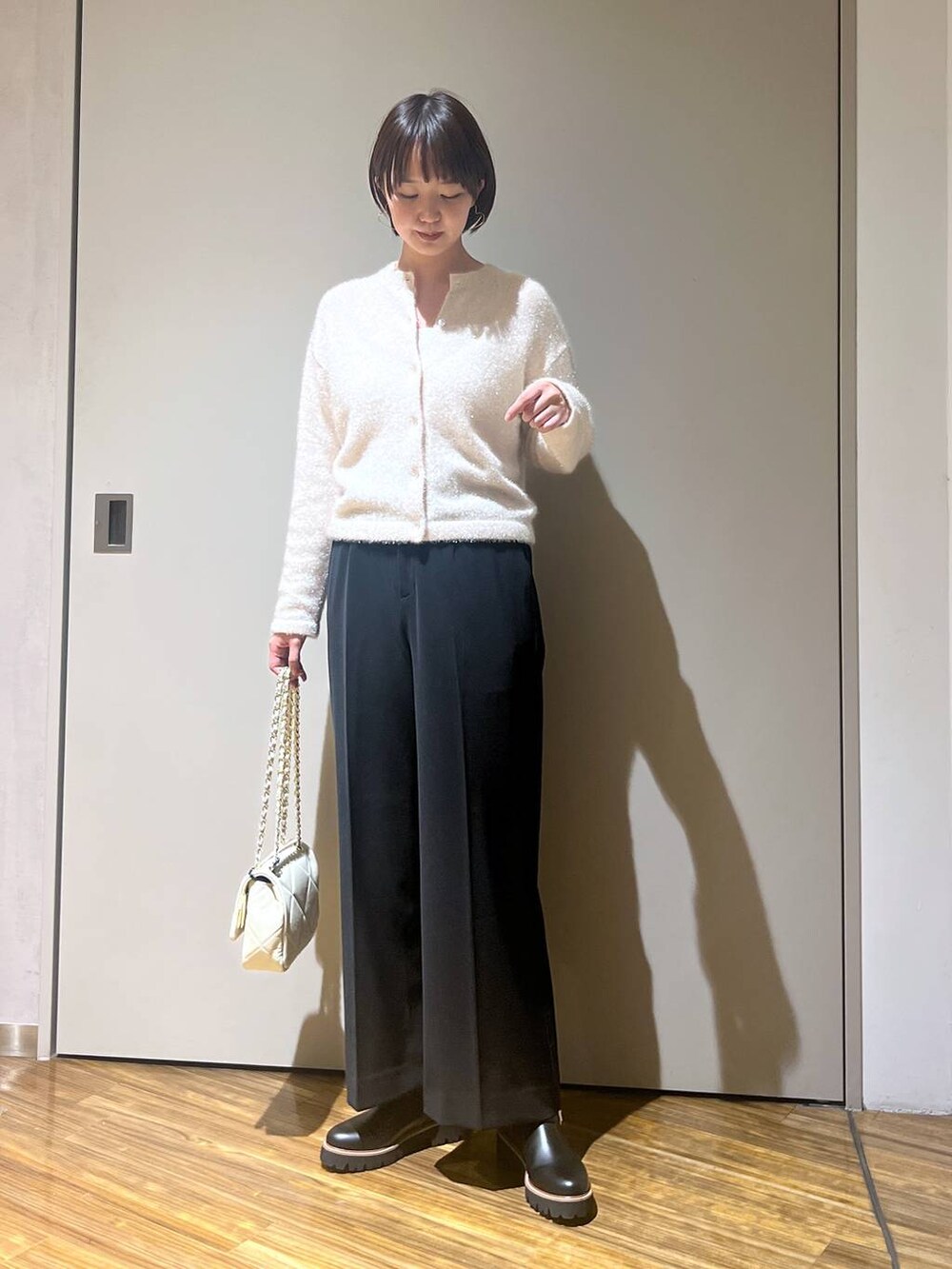 ホワイト系のショルダーバッグ、ホワイト系のニット/セーター、ブラック系のその他パンツを着用したレディースの冬コーディネートの2枚目の写真