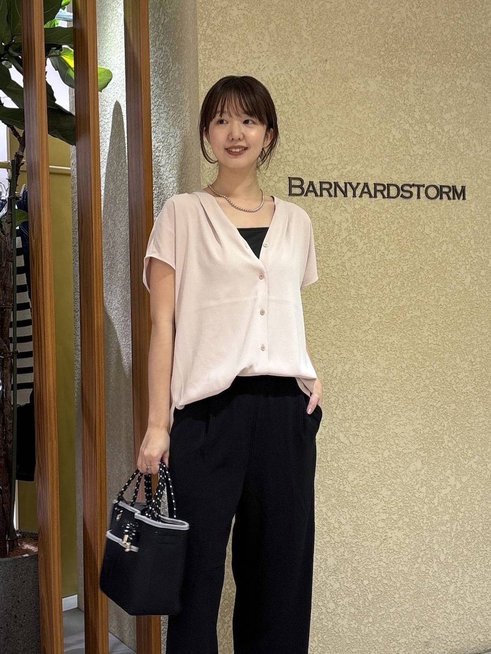 ブラック系のスラックス、ホワイト系のシャツ/ブラウス、ブラック系のトートバッグを着用したレディースの春コーディネートの2枚目の写真