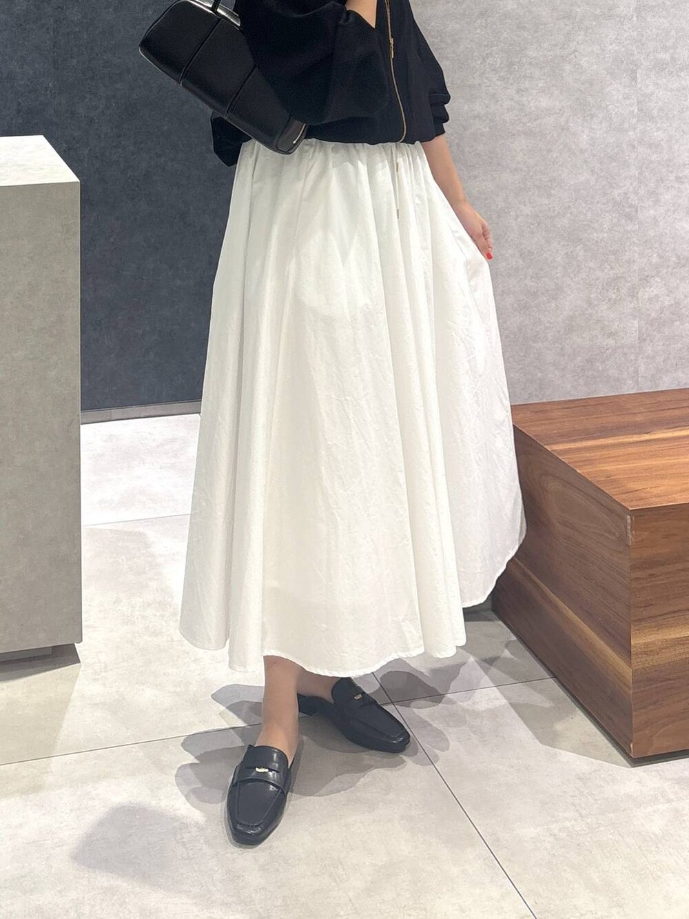 ホワイト系のスカート、ブラック系のローファー、ブラック系のボストンバッグを着用したレディースの春コーディネートの3枚目の写真