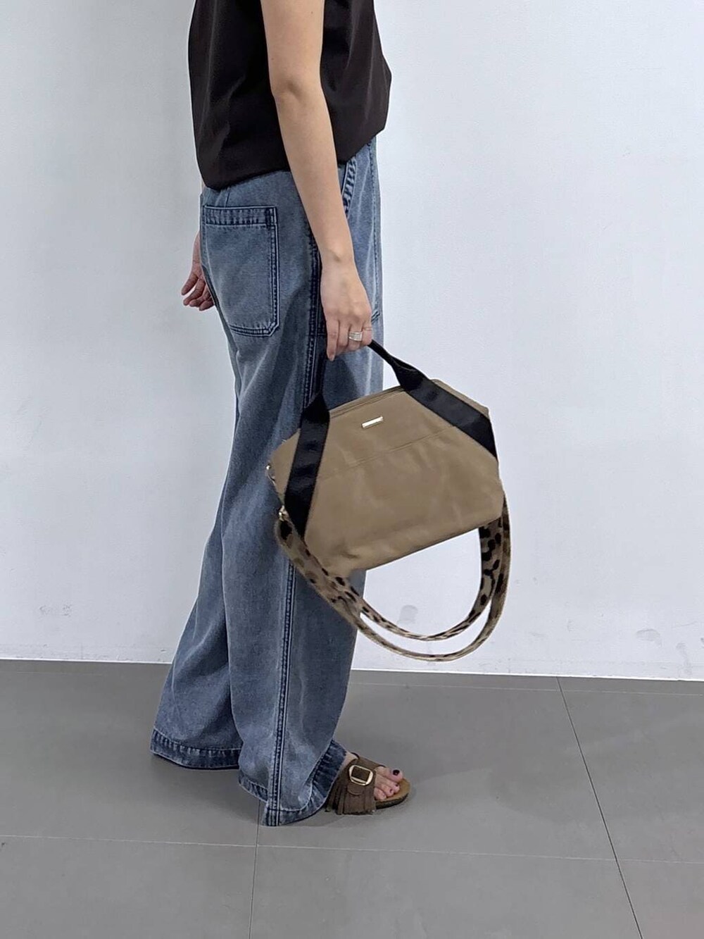 イエロー系のトートバッグ、ブラウン系のTシャツ/カットソー、ブルー系のデニムパンツを着用したレディースの春コーディネートの5枚目の写真