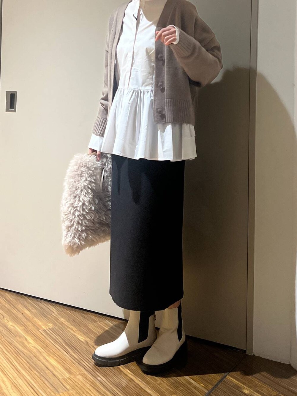 ホワイト系のブーツ、ブラウン系のハンドバッグ、ブラウン系のニット/セーターを着用したレディースの冬コーディネートの2枚目の写真