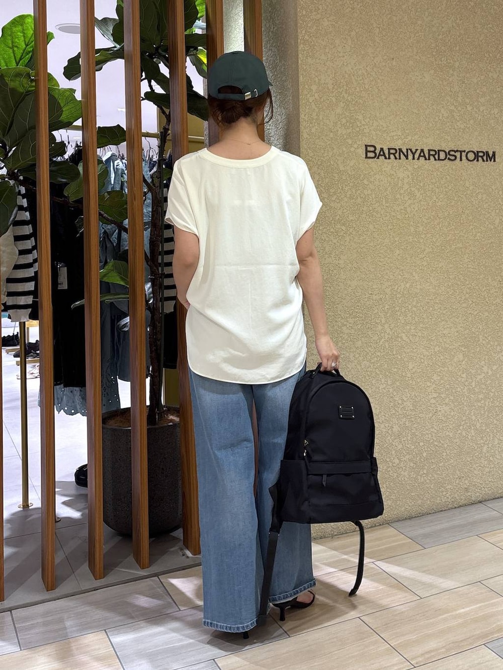 ブルー系のデニムパンツ、ブラック系のバックパック/リュック、ホワイト系のシャツ/ブラウスを着用したレディースの春コーディネートの3枚目の写真