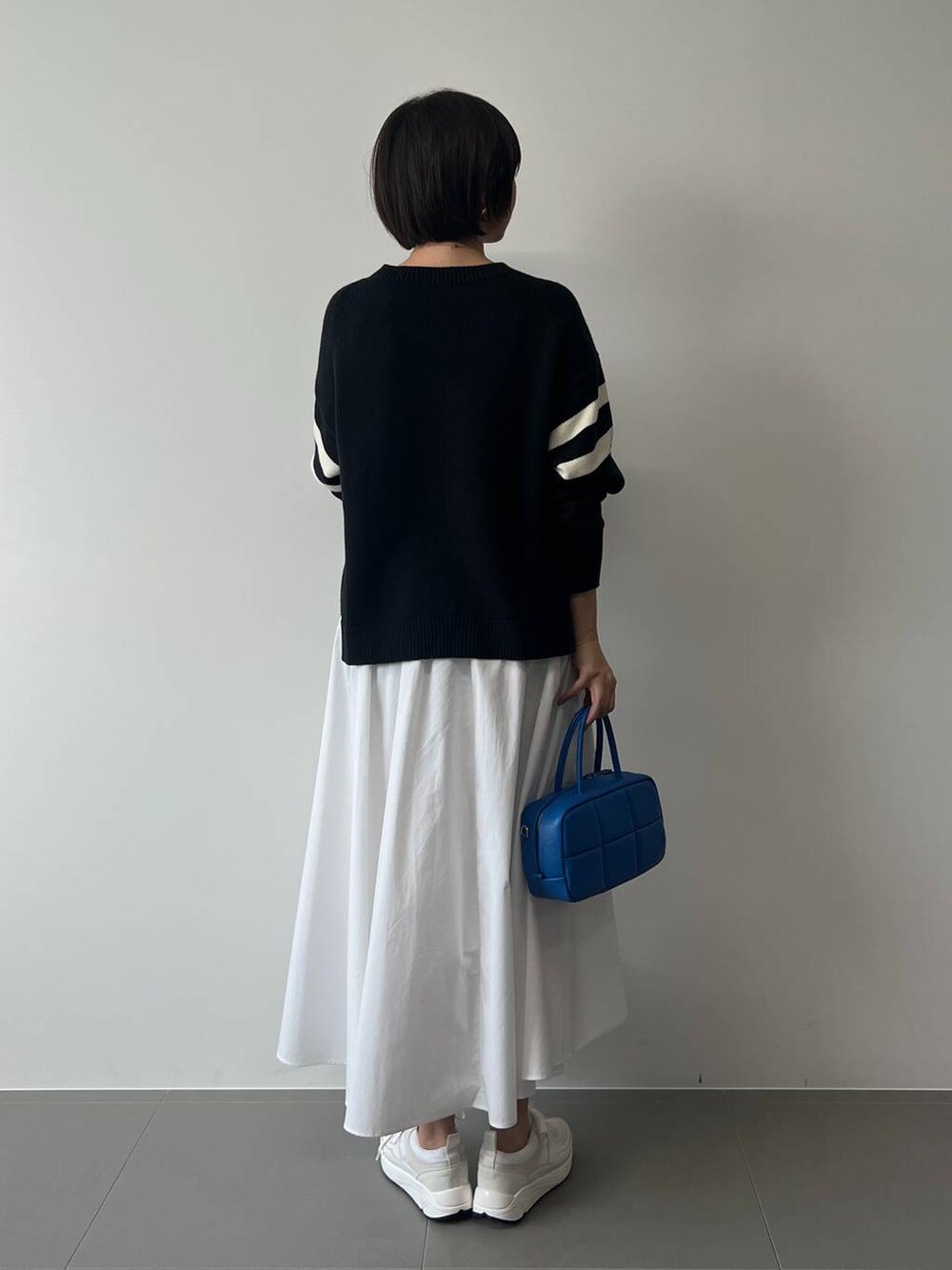 ブルー系のニット/セーター、ホワイト系のスニーカー、ブルー系のハンドバッグを着用したレディースの冬コーディネートの5枚目の写真