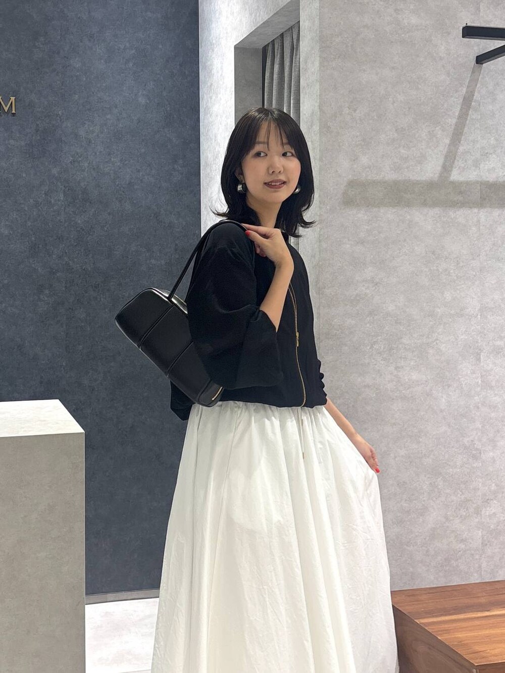 ホワイト系のスカート、ブラック系のローファー、ブラック系のボストンバッグを着用したレディースの春コーディネートの2枚目の写真