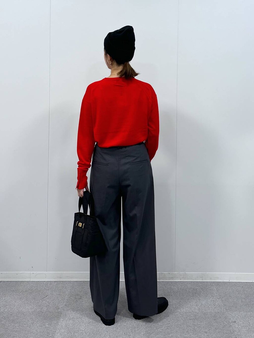 グレー系のスラックス、ブラック系のトートバッグ、レッド系のニット/セーターを着用したレディースの秋コーディネートの5枚目の写真