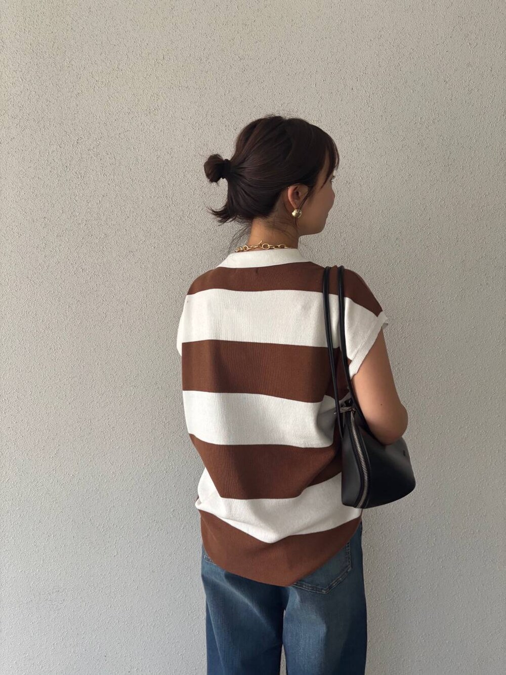ブルー系のデニムパンツ、ブラック系のトートバッグ、イエロー系のニット/セーターを着用したレディースの夏コーディネートの5枚目の写真