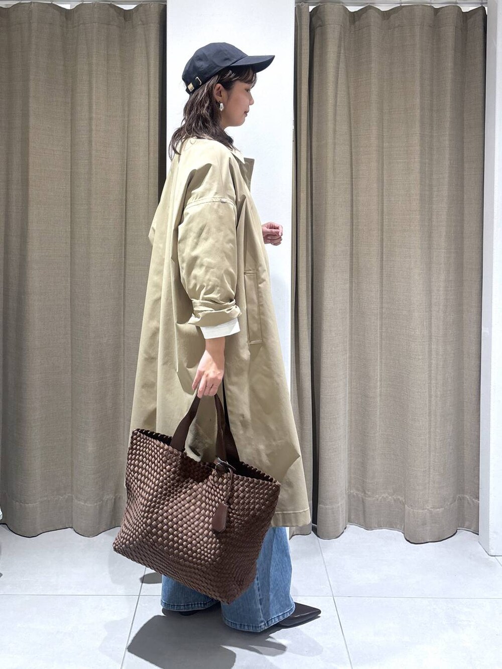 ホワイト系のTシャツ/カットソー、ブルー系のデニムパンツ、ベージュ系のステンカラーコートを着用したレディースの冬コーディネートの2枚目の写真