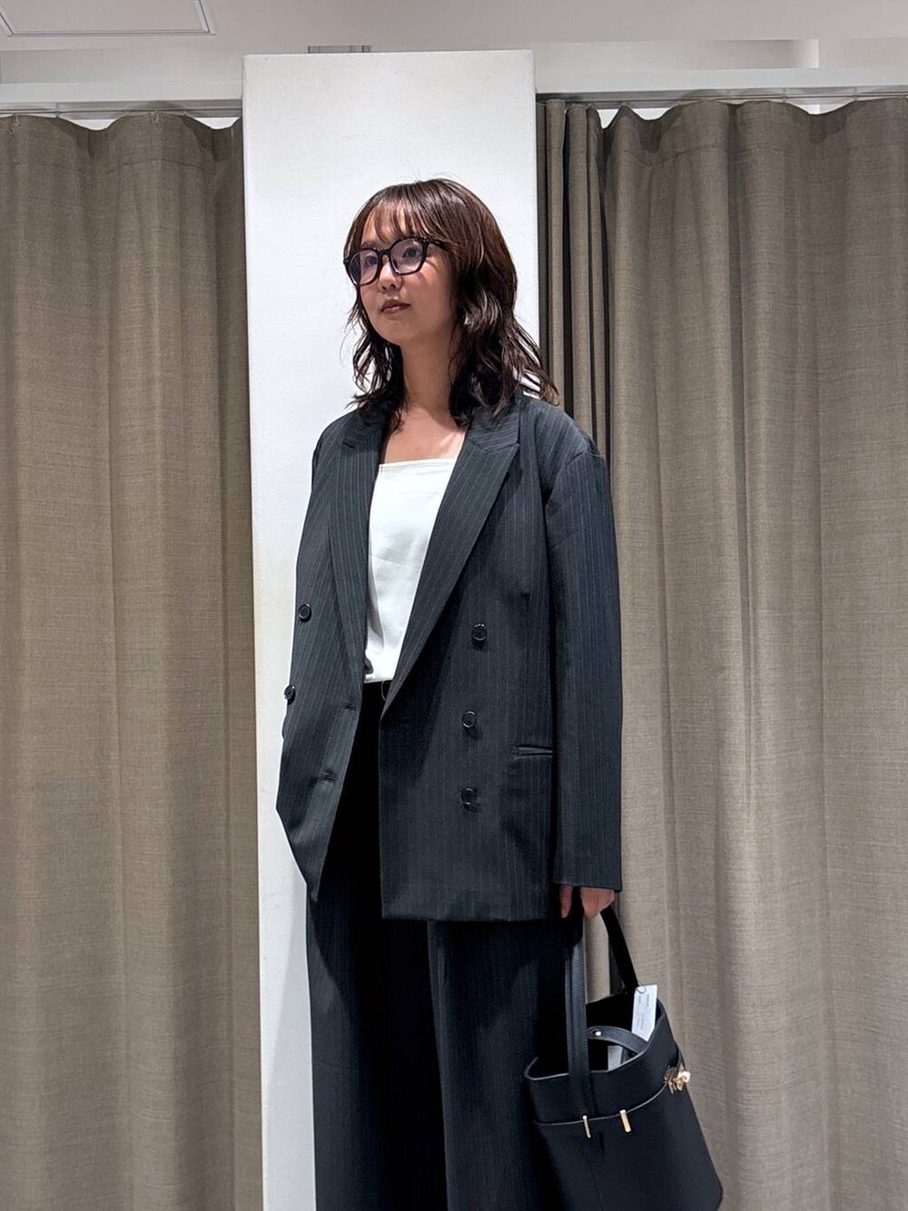 グレー系のスラックス、グレー系のテーラードジャケット、ブラック系のハンドバッグを着用したレディースの秋コーディネートの4枚目の写真