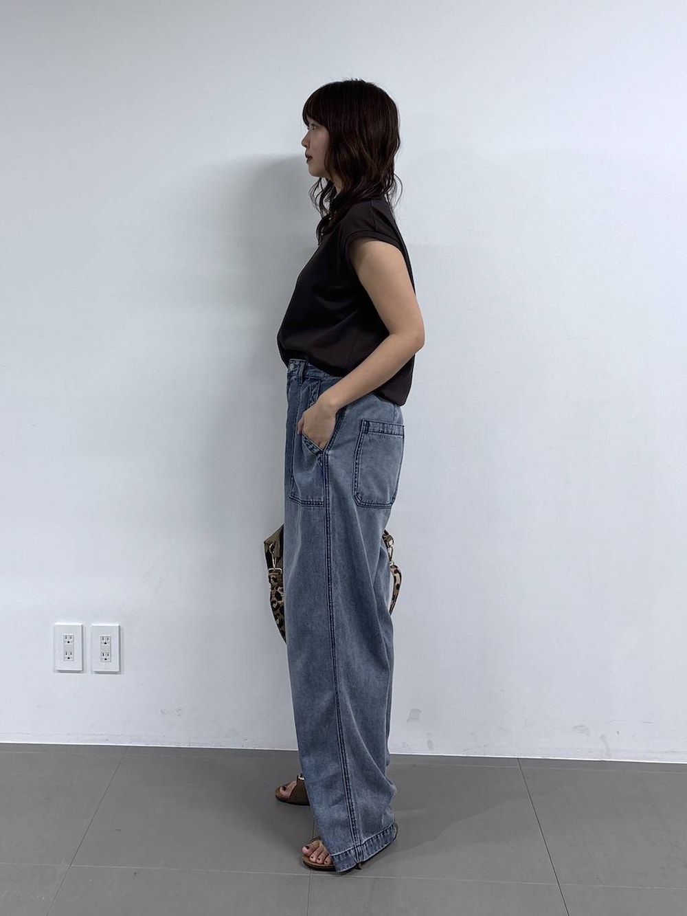 イエロー系のトートバッグ、ブラウン系のTシャツ/カットソー、ブルー系のデニムパンツを着用したレディースの春コーディネートの3枚目の写真