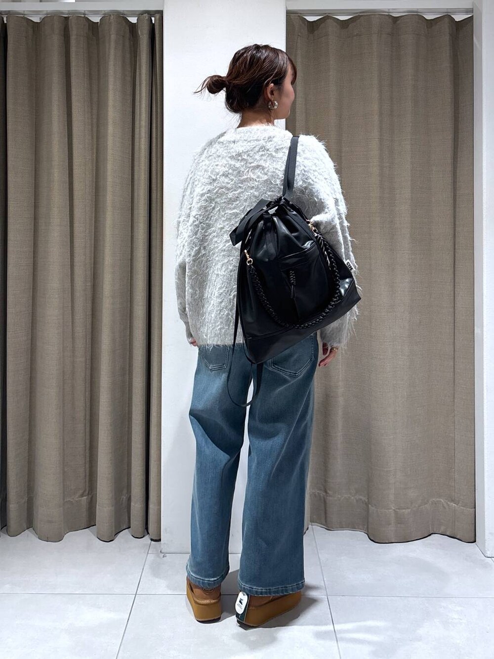 ブラック系のバックパック/リュック、ブルー系のデニムパンツ、イエロー系のブーツを着用したレディースの秋コーディネートの2枚目の写真