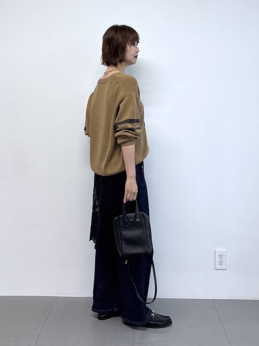 ブラック系のローファー、ブルー系のデニムパンツ、ベージュ系のニット/セーターを着用したレディースの秋コーディネートの3枚目の写真