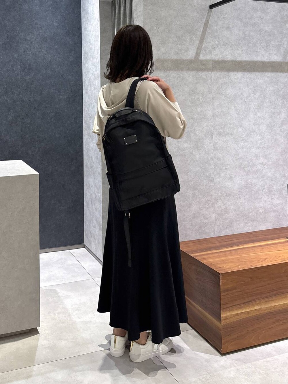 ベージュ系のスカート、ブラック系のバックパック/リュック、ホワイト系のスニーカーを着用したレディースの春コーディネートの4枚目の写真