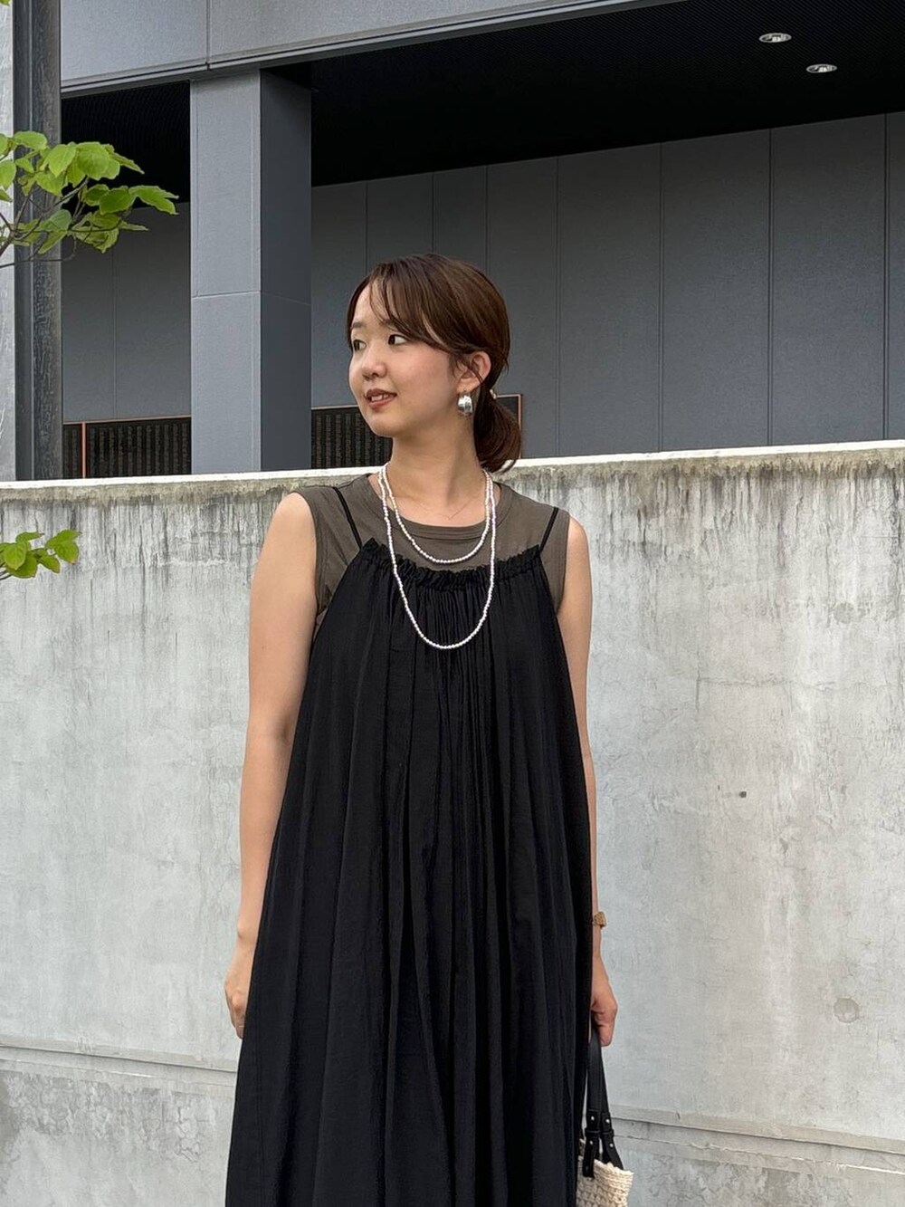 ブラック系のワンピース、ブラック系のデニムパンツ、ホワイト系のトートバッグを着用したレディースの夏コーディネートの2枚目の写真