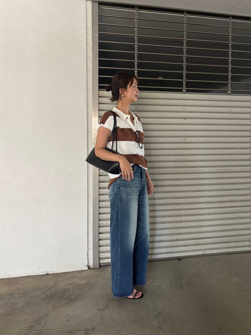 ブルー系のデニムパンツ、ブラック系のトートバッグ、イエロー系のニット/セーターを着用したレディースの夏コーディネートの3枚目の写真