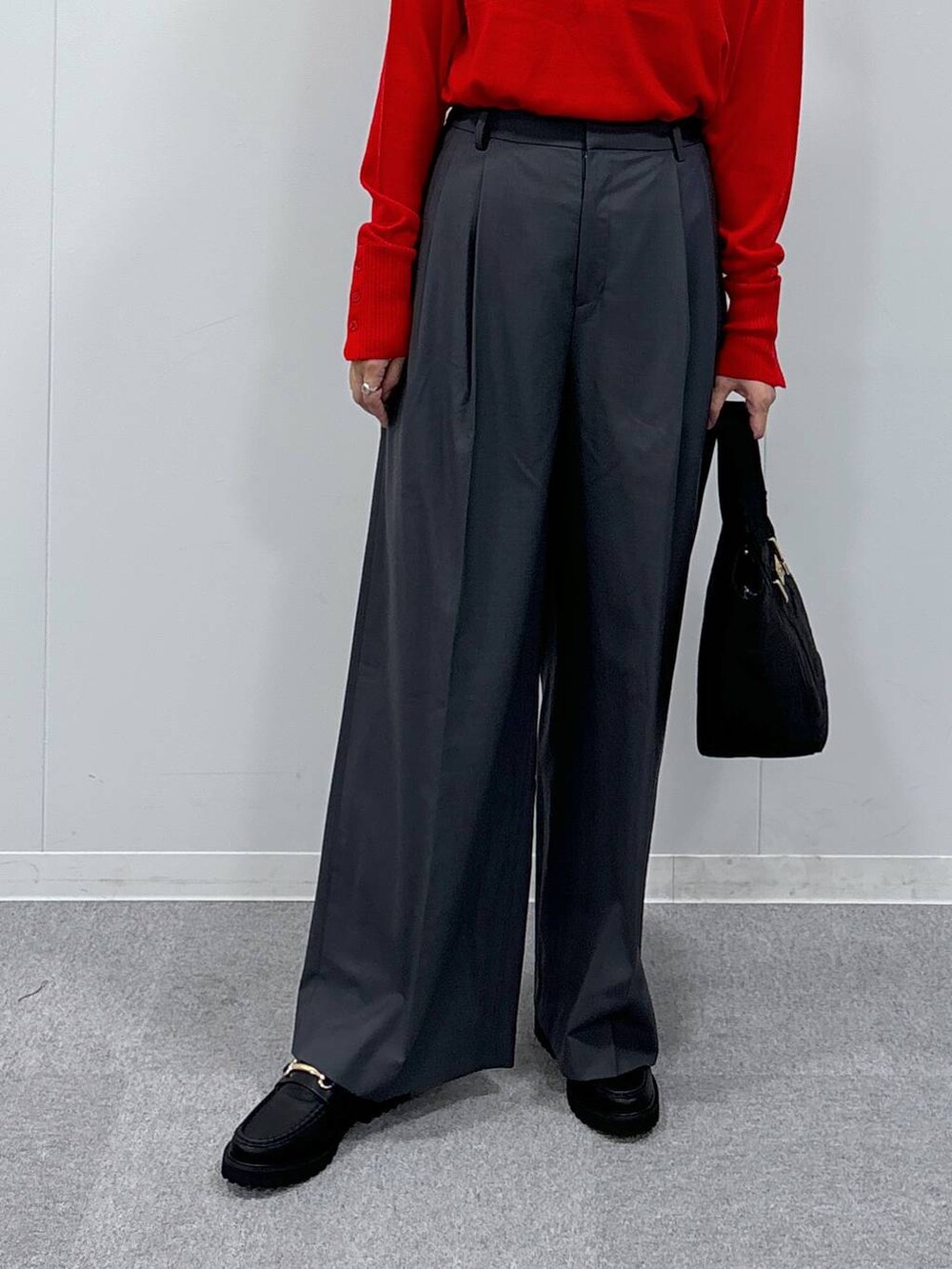 グレー系のスラックス、ブラック系のトートバッグ、レッド系のニット/セーターを着用したレディースの秋コーディネートの4枚目の写真