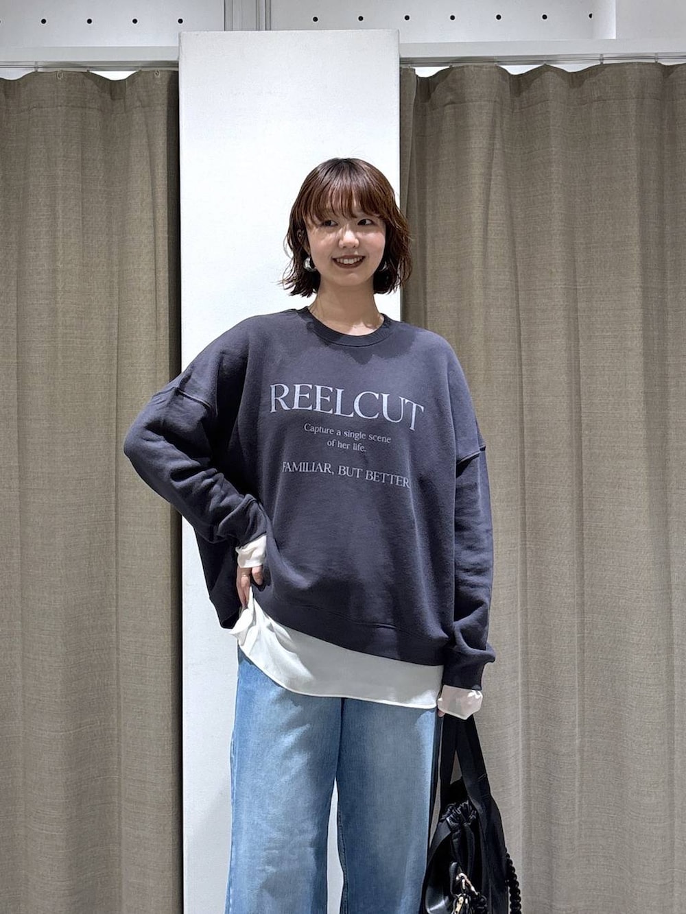 グレー系のスウェット、ブラック系のバックパック/リュック、ブルー系のデニムパンツを着用したレディースの秋コーディネートの2枚目の写真