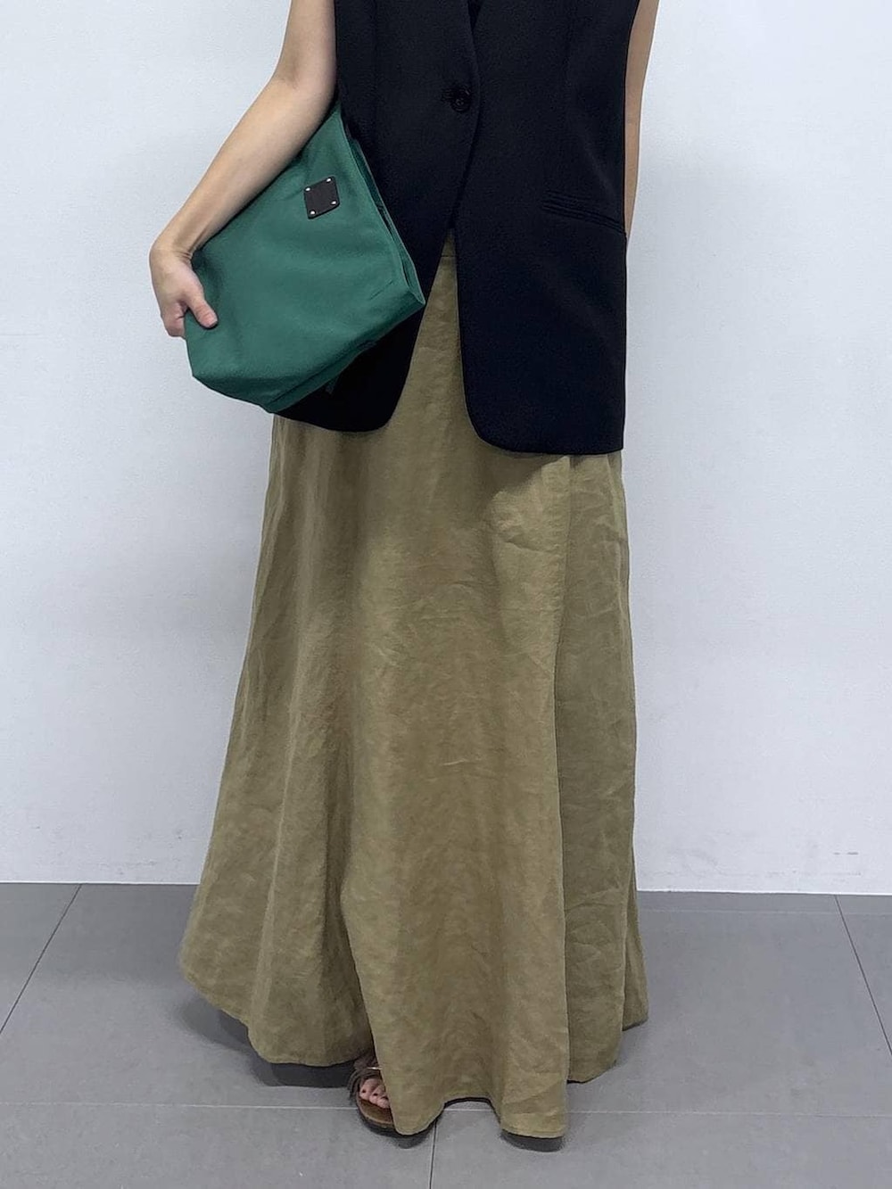 グリーン系のトートバッグ、ベージュ系のスカートを着用したレディースの春コーディネートの4枚目の写真